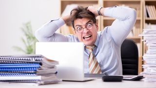 Angry man ripping out his hair in front of his laptop