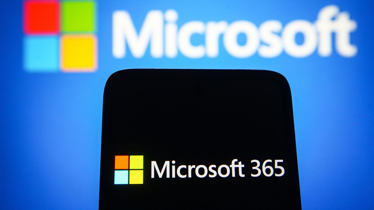 Microsoft 365 logo and branding pictured on a smartphone screen with Microsoft symbol in background.