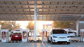 A white Tesla Model X parked at a Tesla Supercharger station