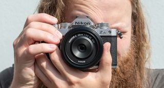 A man holding the Nikon Z fc camera up to his face