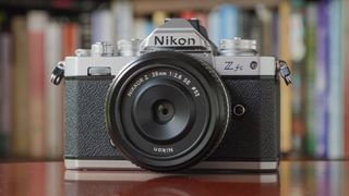 The Nikon Zfc camera sitting on a red table in front of a bookcase