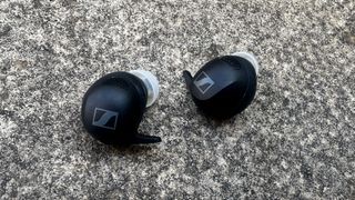 Sennheiser Momentum Sport earbuds on grey table background