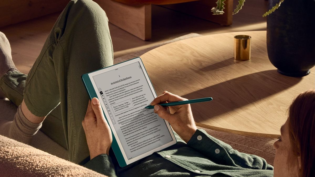 A woman lying on a couch and adding annotations to an ebook on the Metallic Jade Amazon Kindle Scribe (2024)