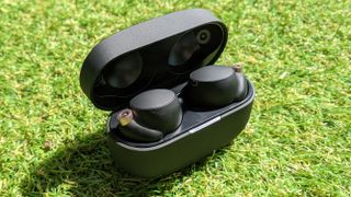 The sony wf-1000xm4 true wireless earbuds in their charging case on a grass surface