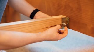 A person fixing a squeaky bed frame