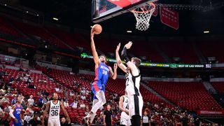 Jalen Slawson of the Detroit Pistons jumping into the air to dunk a basketball into the basket during a basketball game against the Utah Jazz. In the background, other players and the crowd stand can be seen.