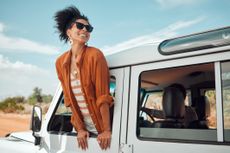 A woman leans out of a jeep while on safari.