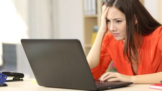 A worried woman sitting at a surface and using a laptop