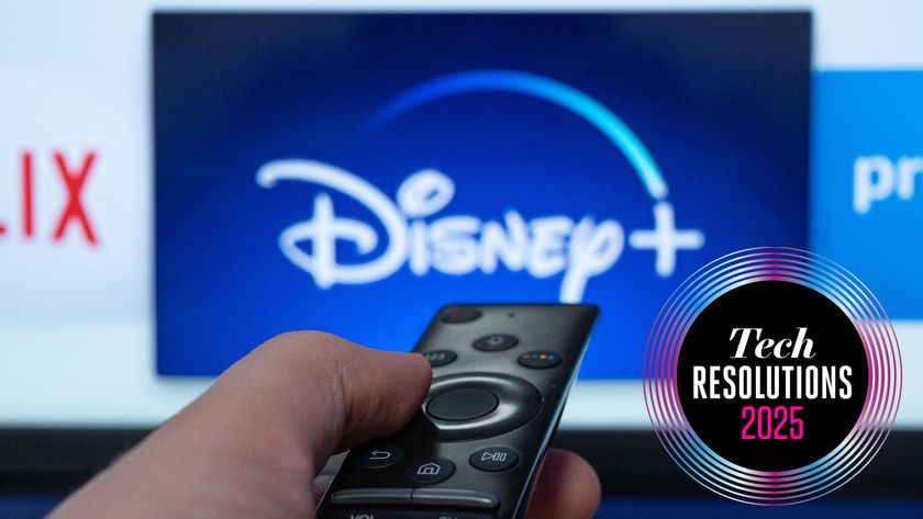 A person holding a remote to a TV screen showing the Disney Plus, Netflix and Prime Video logos