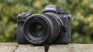 Nikon Z7 II set forfra står på en træstol med buske i baggrunden