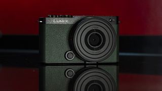 Panasonic Lumix S9 camera in Dark Olive color on a rich red reflective surface