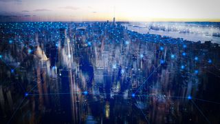 A photo of the New York City skyline overlaid with blue lines to represent IoT security strategy, via a series of interconnected devices.