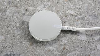 The back face of the ESR Qi2 Mini Wireless Charger against a light grey stone-effect surface.