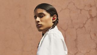 A girl wearing the Beats Studio Buds in red.