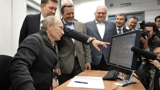 Vladimir Putin being shown something on a computer monitor