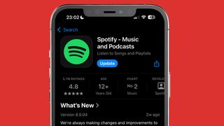 An iPhone on a red background showing the Spotify app being updated in the App Store