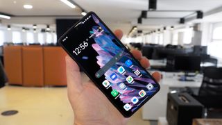 En Oppo Find N2 Flip hålls upp i ett kontor med framsidan vänd mot kameran.