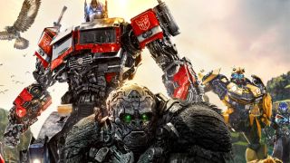 Still from the movie Transformers: Rise of the Beasts (2023). Here we see 5 Transformers standing together. From left to right, there is Optimus Prime (large blue and red robot that can turn into a truck), Optimus Primal (a robot gorilla with piercing green lights for eyes), and then the yellow Transformer Bumblebee. To the left there appear 2 other Transformers (a mechncialy bird in the sky and a blue blocky robot in the background.