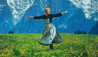 Julie Andrews as Maria smiling in a field of flowers during a scene in the Disney movie The Sound of Music.