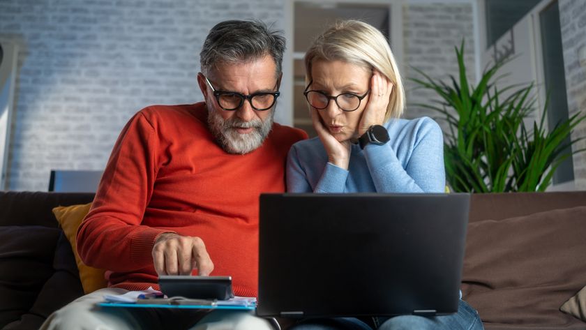 A man and a woman sitting on a couch and the woman has a laptop on her lap