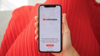 Woman holding phone showing YouTube Premium logo