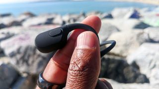 Someone holding the Shokz OpenRun bone conduction headphones between their fingertips.