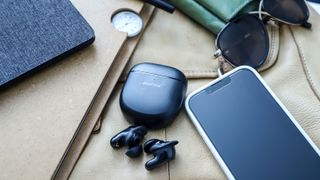 Les Bose QuietComfort Earbuds II sont sortis de leur étui à proximité d'un iPhone.