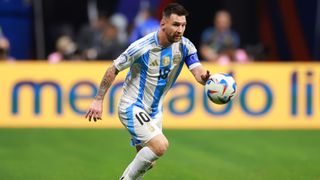Lionel Messi chases the ball at Copa America 2024 in the blue and white striped Argentina first kit.