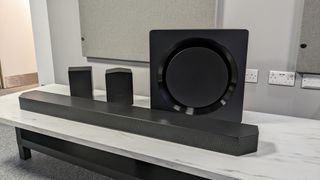 Samsung HW-Q995D -soundbar, subwoofer ja takakaiuttimet asetettuna valkoiselle pöydälle