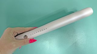 Reviewer holding T3 SinglePass Smooth X flat irons with a turquoise background