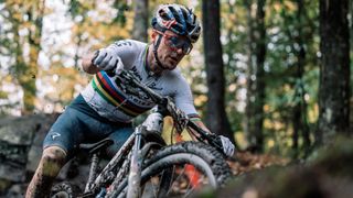 Olympic Mountain Bike Cross champion Tom Pidock, on his bike, spattered with mud, ahead of the 2024 Paris Games.