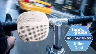 Bose SoundLink Micro speaker in white attached to bike handlebars with a yellow taxi in the distance and rain