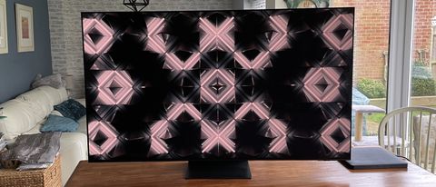 Samsung S95C OLED TV op een houten tafel met een abstract beeld op het scherm