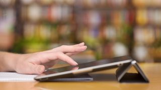 A person&#039;s hand using a tablet, up close and from the side