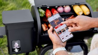 The Brisk It Zelos-450 being used to grill chicken, and veggies (onions, bepper, sweetcorn) while the user gets advice from the Vera app