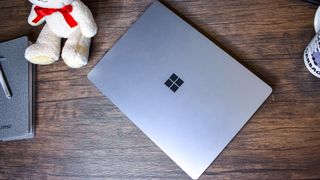 A closed Surface Laptop 4 on a coffee table next to a notebook and a coffee cup