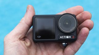 DJI Osmo Action 4 camera in the hand with swimming pool background