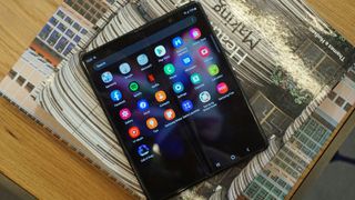 Samsung Galaxy Z Fold 3 Samsung Galaxy Z Fold 3 ligger åben med tændt skærm på en stak bøger