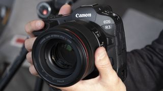 Two hands holding the Canon EOS R3 mirrorless camera