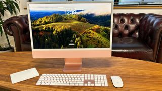 M3 iMac 24-inch (2023) on a wooden desk with Magic Keyboard and Mouse.