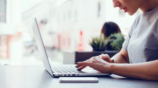 Woman typing on MacBook in cafe