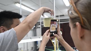 A scientist holds up a jar containing the rotifers which will be counted using the AI tool