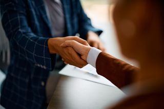 Close up of coworkers handshaking while greeting during business meeting in the office