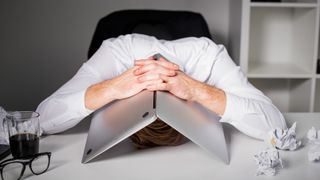 Windows 10 user looking frustrated with their head underneath an open laptop