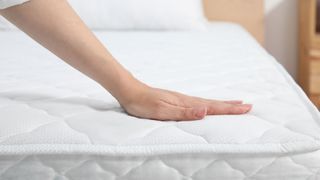 A woman's hand checks a mattress's motion isolation