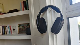 The Sennheiser HD-660S2 over-ear headphones hanging on a hook near a window