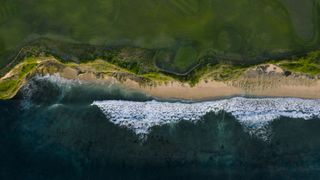 A bird&#039;s eye view of the sea meeting a beach