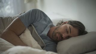 How much sleep do you need: A man in a blue t-shirt sleeps on his side