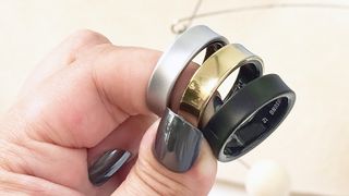 Three Samsung Galaxy Rings in a user's hand shown in silver, gold and black