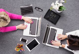 two creative women working on laptops